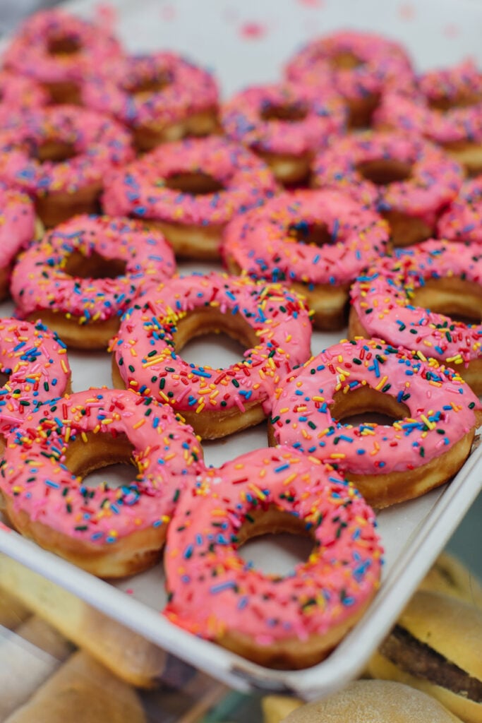 Photo of a baking tray of fresh pink-frosted donuts for Life & Thyme.