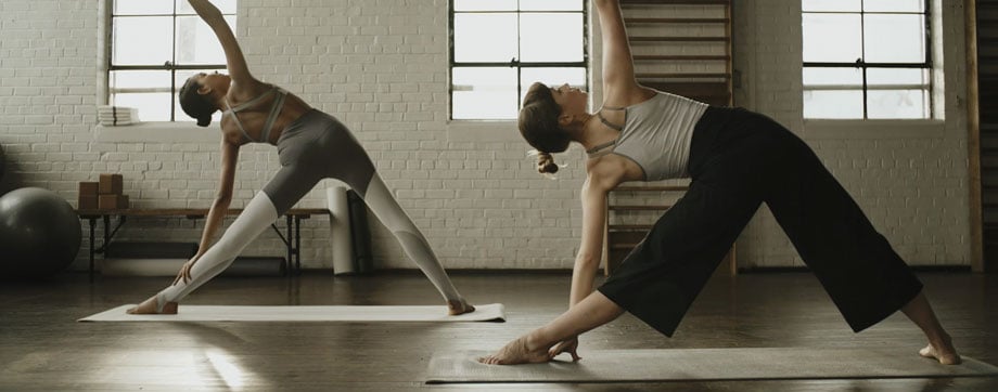 Still of two women doing stretches inside a studio taken by Chicago-based fitness photographer Marcus Smith. A campaign for Nike Style Guide. 