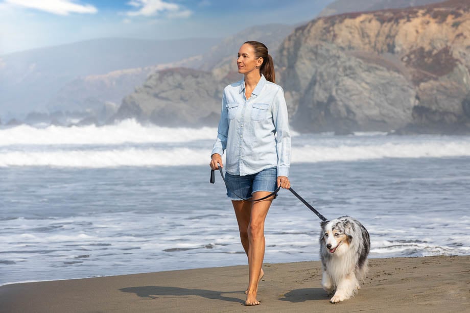 Photo of a woman walking her dog along the beach taken by San Francisco-based lifestyle photographer Mark Rogers. 