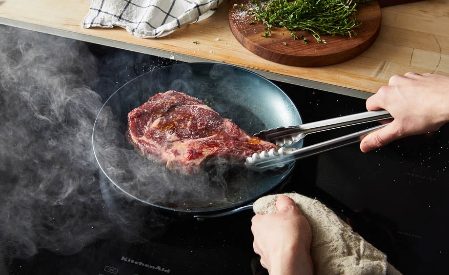 Photo of a man pan-frying a steak taken by New York-based food photographer Mark Weinberg. 