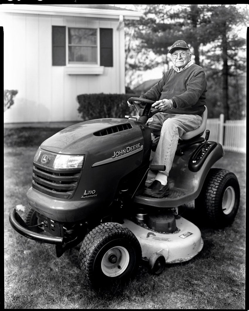Michael Wilson's black and white portrait of a man riding a John Deere tractor for Down East Magazine 