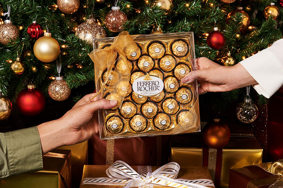 Two hands holding Ferrero Roche in front of Christmas tree shot by Morgan Ione.