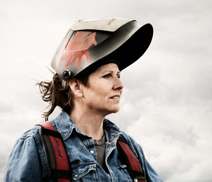 Outdoor portrait photo of a female blue collar worker with a face visor on her head taken by Atlanta-based industrial photographer Nick Burchell. 