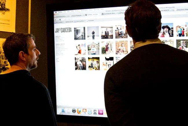 Two creatives looking at a photographer's website on a large screen during a portfolio event