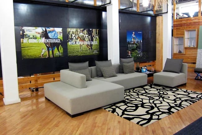 A lobby with large print ads, wood decals and a sofa near a printed rug