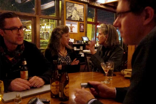 A few people gathered around a table at a pub, having conversation