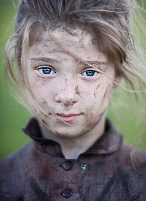 Close up photograph of a young actress with mud on her face for the feature-length film No Place On Earth.