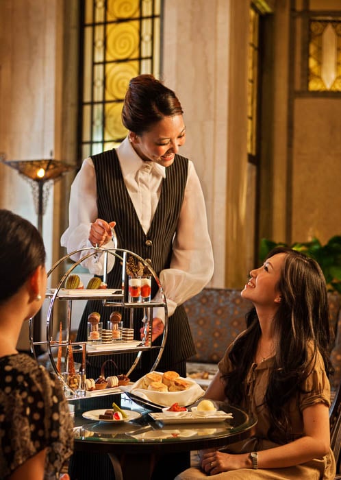 Photo of a hotel waitress serving sweets to two women taken by Singapore-based hospitality photographer Rory Daniel. 