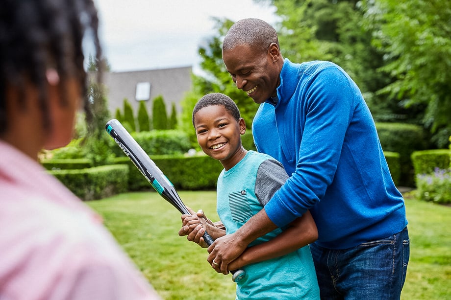 Photo of an African American grandparent teaching his grandson to use a baseball bat taken by Atlanta-based lifestyle photographer Scott Areman. 