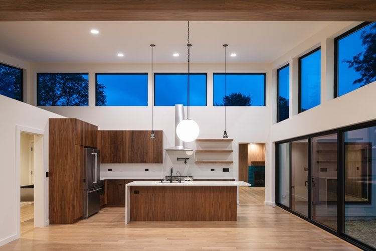 Interior shot of a wide open modern space with a kitchen area at the center by Serhii Chrucky.