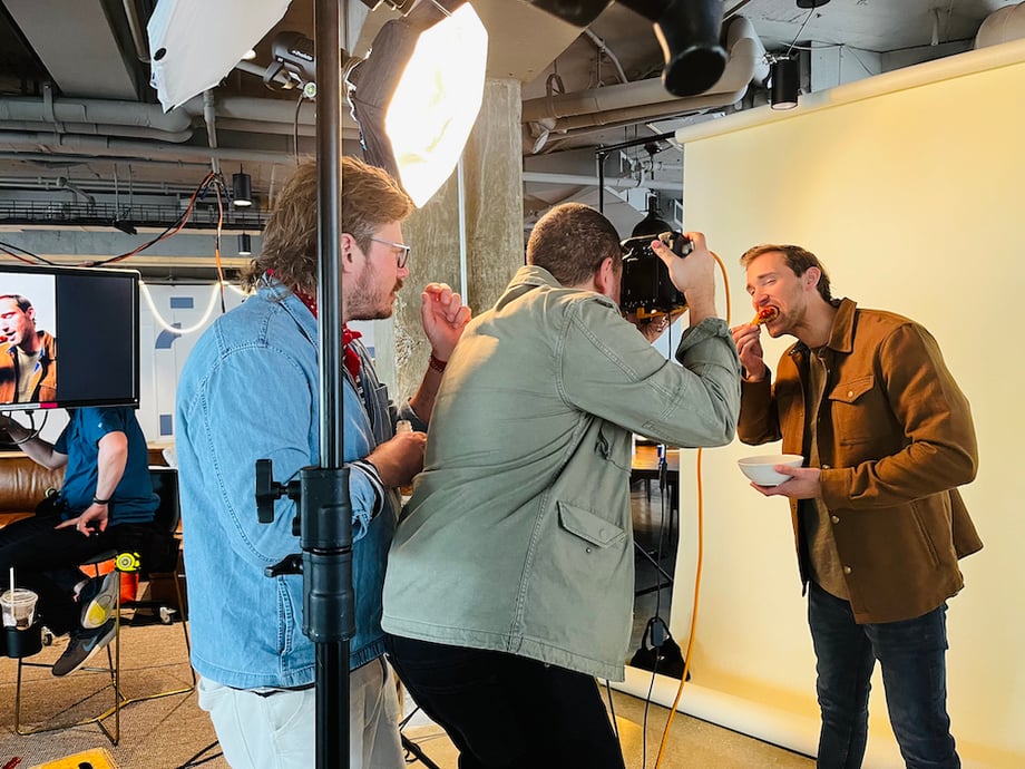 A BTS image of executive producer Bryan directing talent while the photographer takes a photograph.