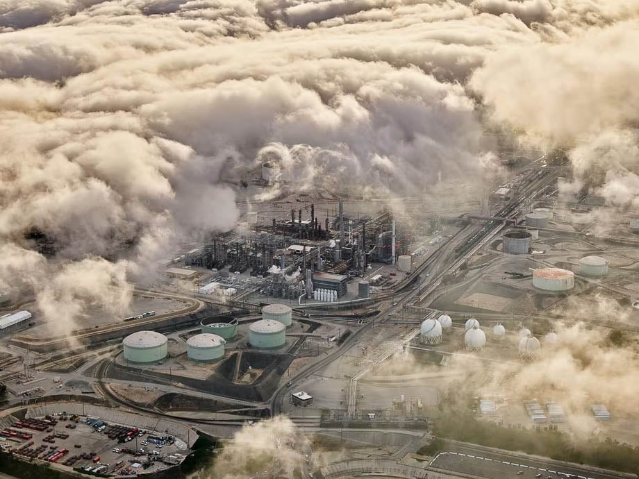 Aerial photo of a factory of powerplant shrouded by clouds taken by Los Angeles-based industrial photographer Spencer Lowell. 