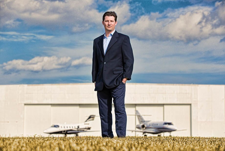 Photo of a business person on an airplane runway with two planes behind him taken by Miami-based corporate photographer Steve Boxall. 
