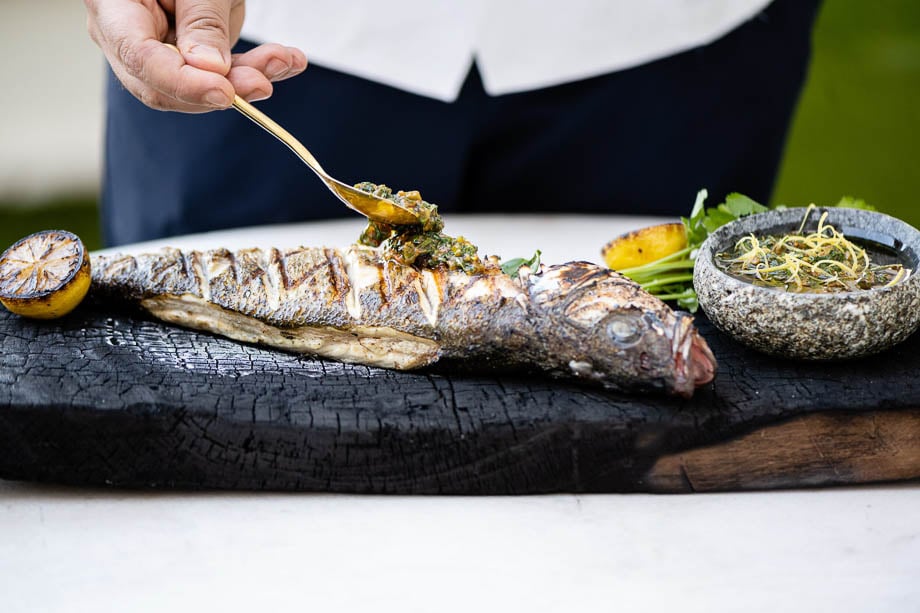 Photo of a chef topping a grilled fish with dressing, taken by Los Angeles-based food photographer Teal Thomsen.