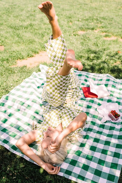 Photo of a woman on a picnic blanket with a book and strawberries taken by Los Angeles-based lifestyle photographer Teal Thomsen. 