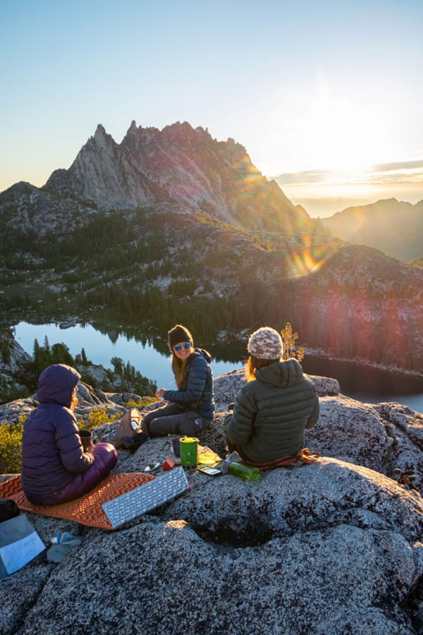 Image of three hikers sitting by a mountain lake by Seattle, Washington-based photographer Tegra Stone Nuess.
