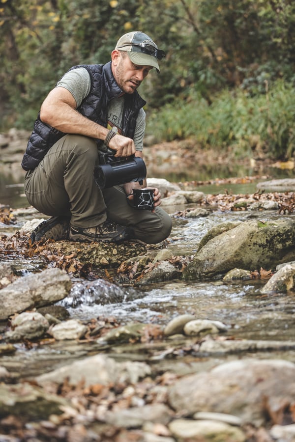 Portrait of a camper at stream-side with thermos and cup by Dallas, Texas-based photographer Terri Glanger.