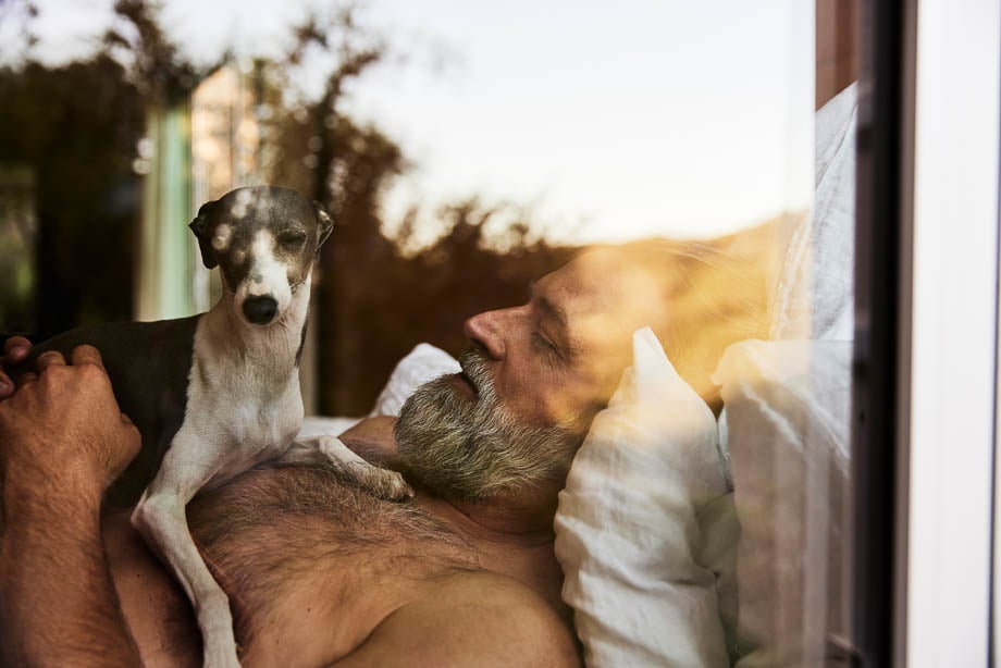 Photo of an old man lying in bed with his dog taken by Los Angeles-based lifestyle photographer Tom Kubik.