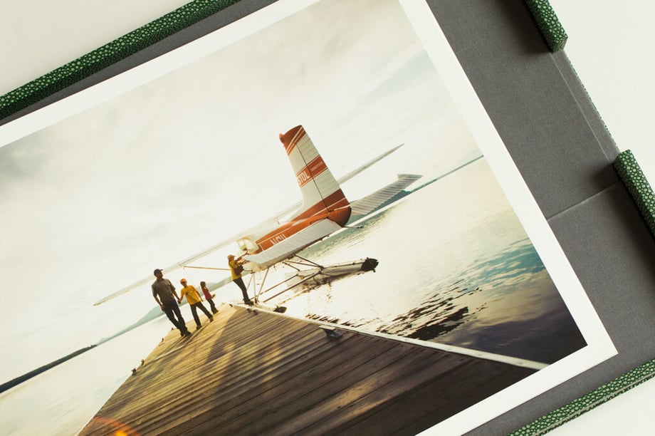 Carl Tremblay's print portfolio open to a photo of a family next to a small airplane.