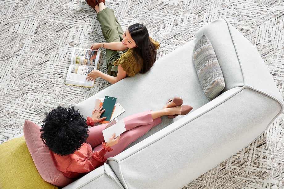 Photo of two women lounging by a sofa flipping through books and brochures taken by Atlanta-based lifestyle photographer duo Tim Wedig and Andrea Laxton of Wedig & Laxton. 