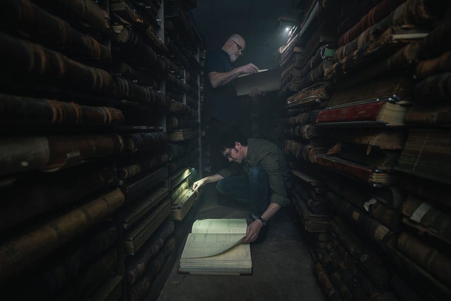Andrew and Chip pore over old books by the light of their cell phones in the shed