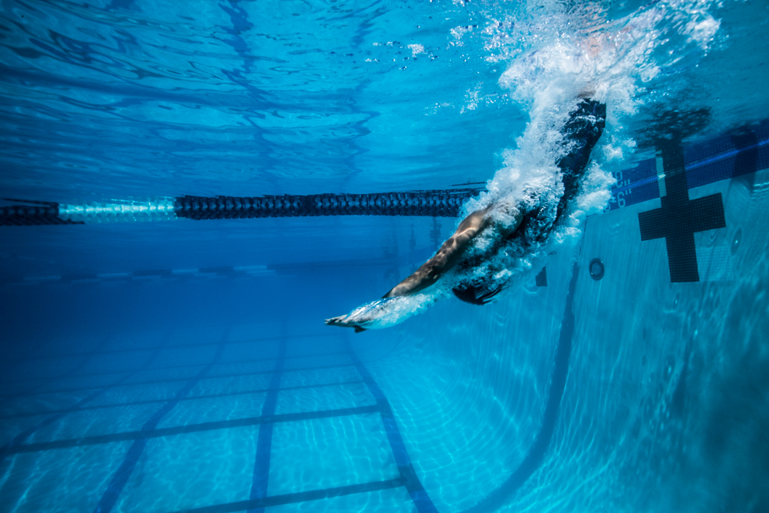 underwater photography showing a swimmer as they dive into a pool