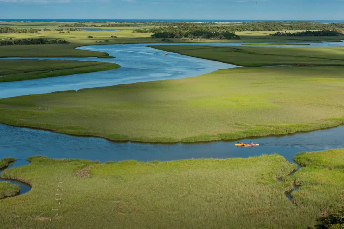 An aerial photograph of two orange kayaks in the lagoons of Bald Head Island, capturd by C2 Photography. 
