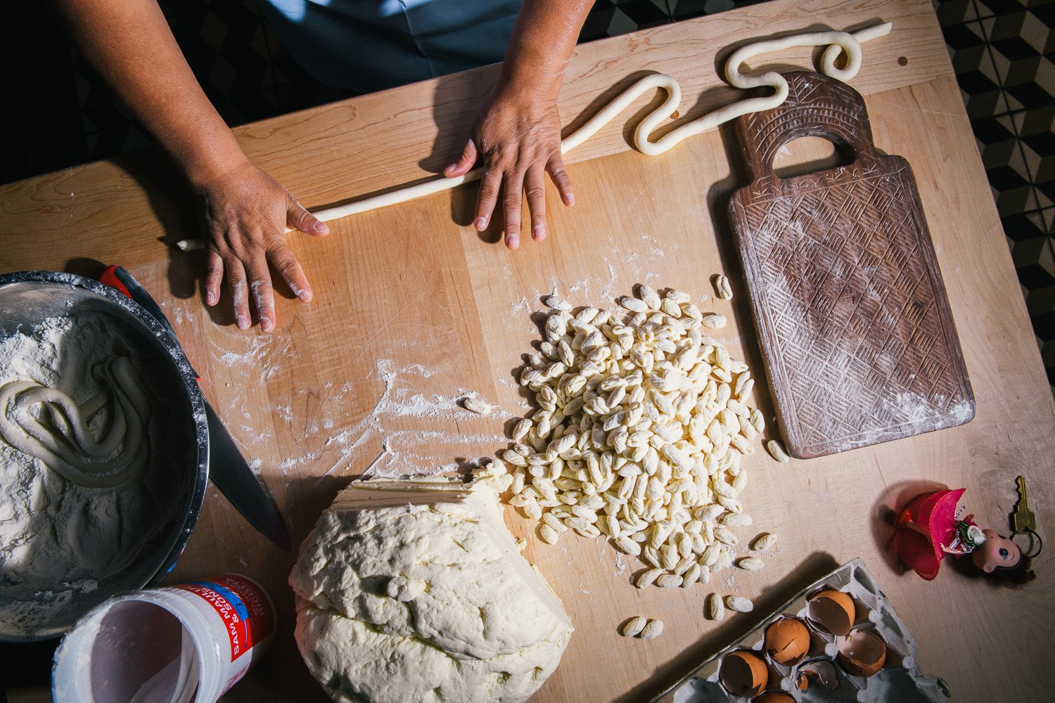 Pasta is rolled and cut on a wooden table in this photo by Lauren V. Allen