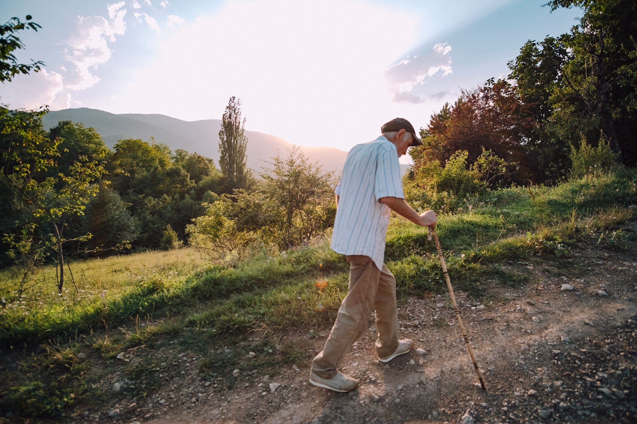 Paata is shown walking a path up a hill using a walking stick in this photo by Dimitri Mais