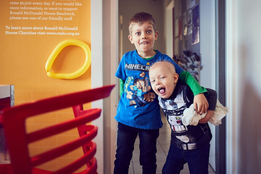 A picture of two children at The Ronald McDonald House in Sydney. The little boy on the left is a head taller has his arm around the other child. Both are making silly faces.