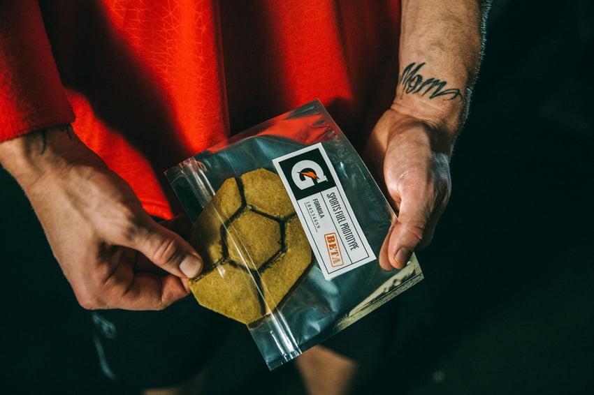 G L Askew II's image for Gatorade. The image shows a man's hands removing a product from a package that says "Sports Fuel Prototype." On one of the person's wrists is a tattoo that says "Mom".