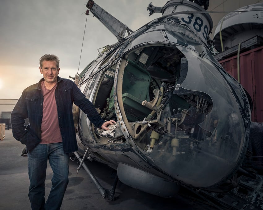 Jeff Berting's portrait of a man leaning on a defunct helicopter with a broken front window.
