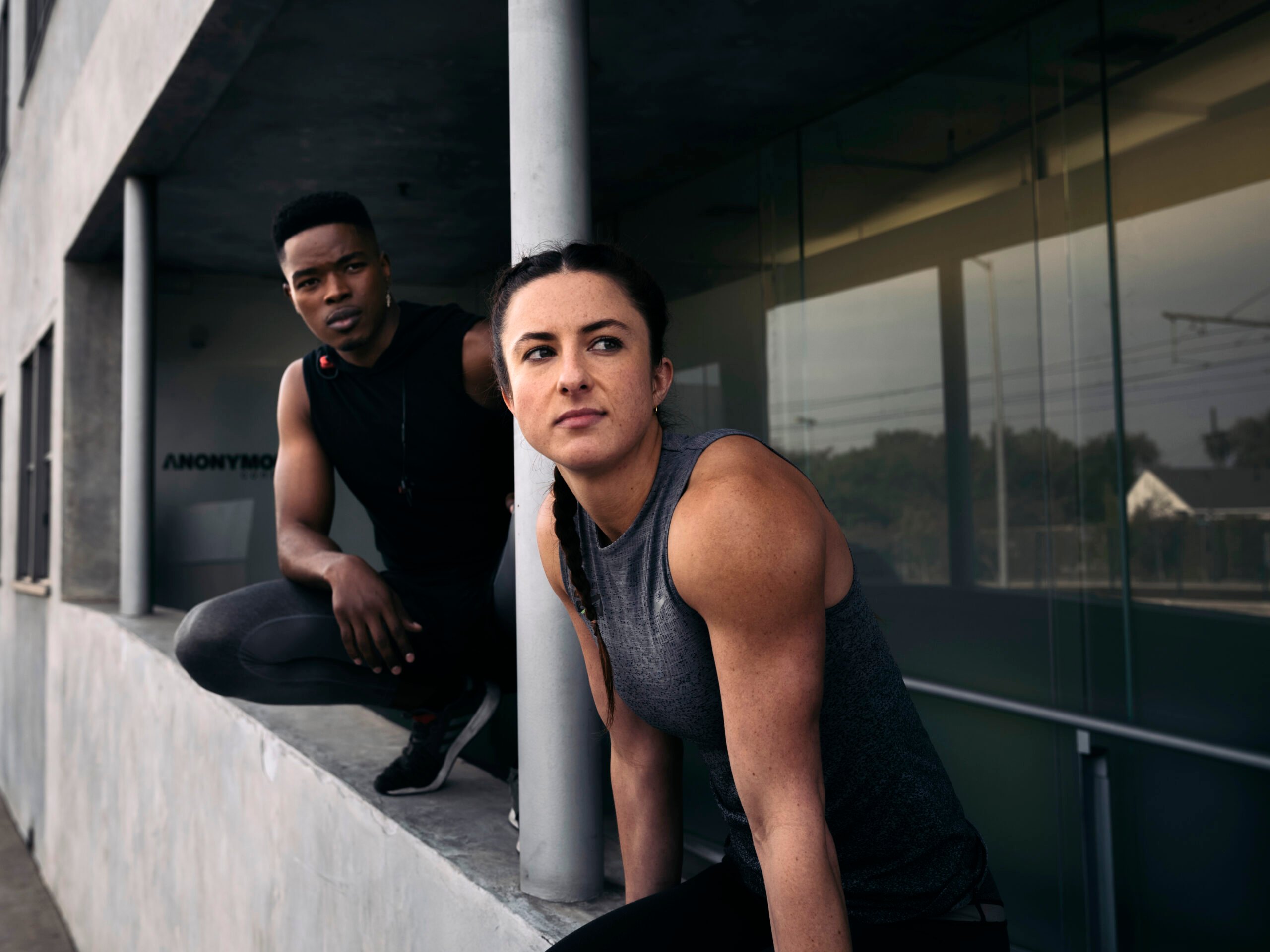Two athletes lean on a concrete wall and look off in the distance in Michael Dorman's photo