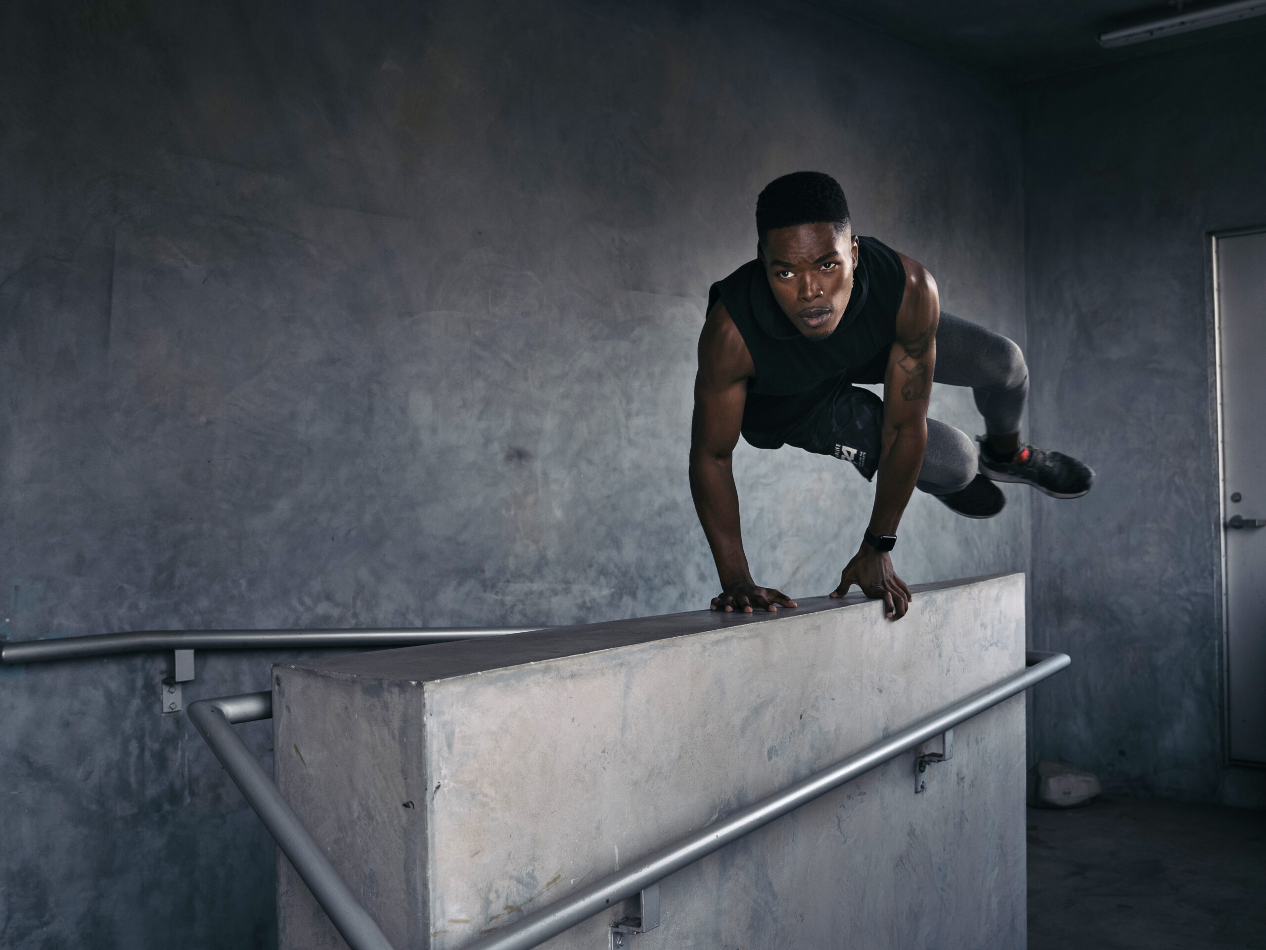 A man performs a parkour move, launching himself over a wall in a stairwell in this photo by Michael Dorman