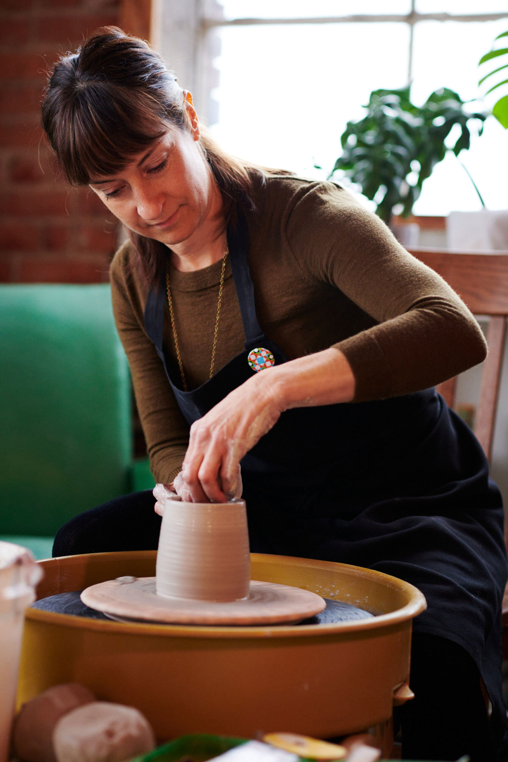 A woman sculpting a clay sculpture on a pottery wheel.