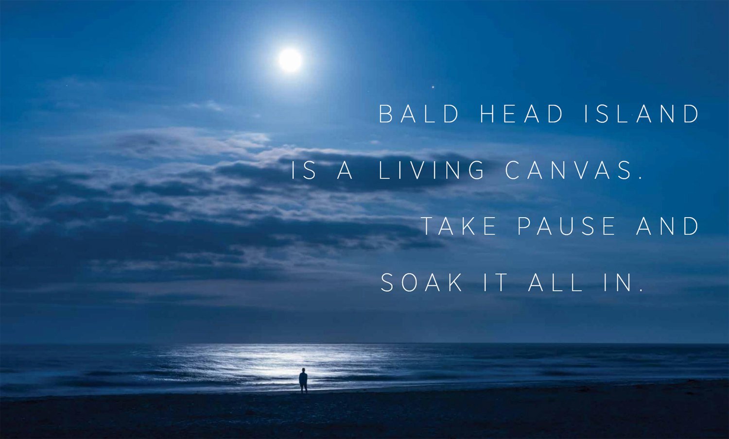 A tear sheet by C2 Photography for Bald Head Island featuring a zoomed-out photo of a lone person standing on the shore looking out at the ocean in the moonlight.