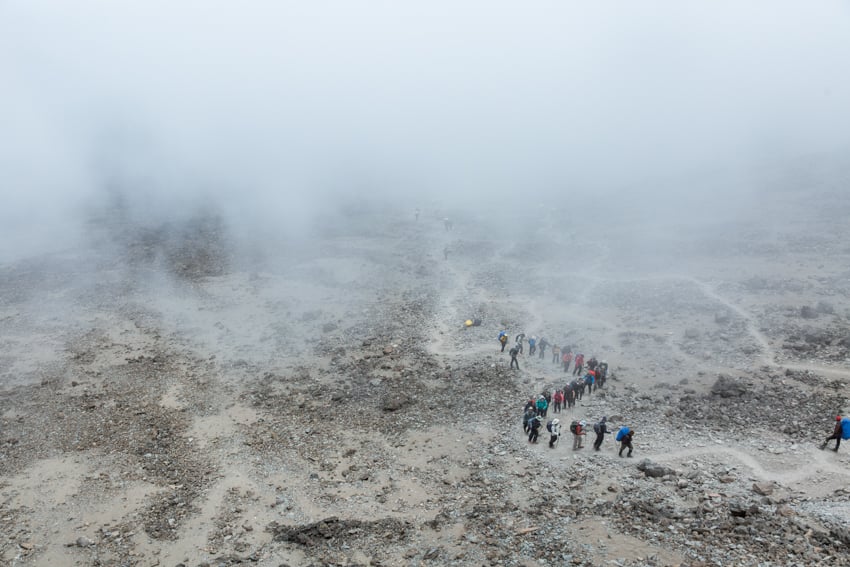 Clay Cook's aerial photo of an expedition of a people climbing in a snaking line on rocky terrain. 