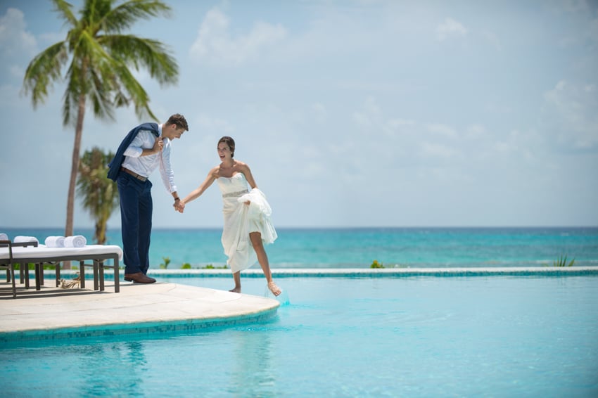 Two happy newlyweds at the resort's pool with the view of the beautiful ocean in the background, photo by Mario Madau