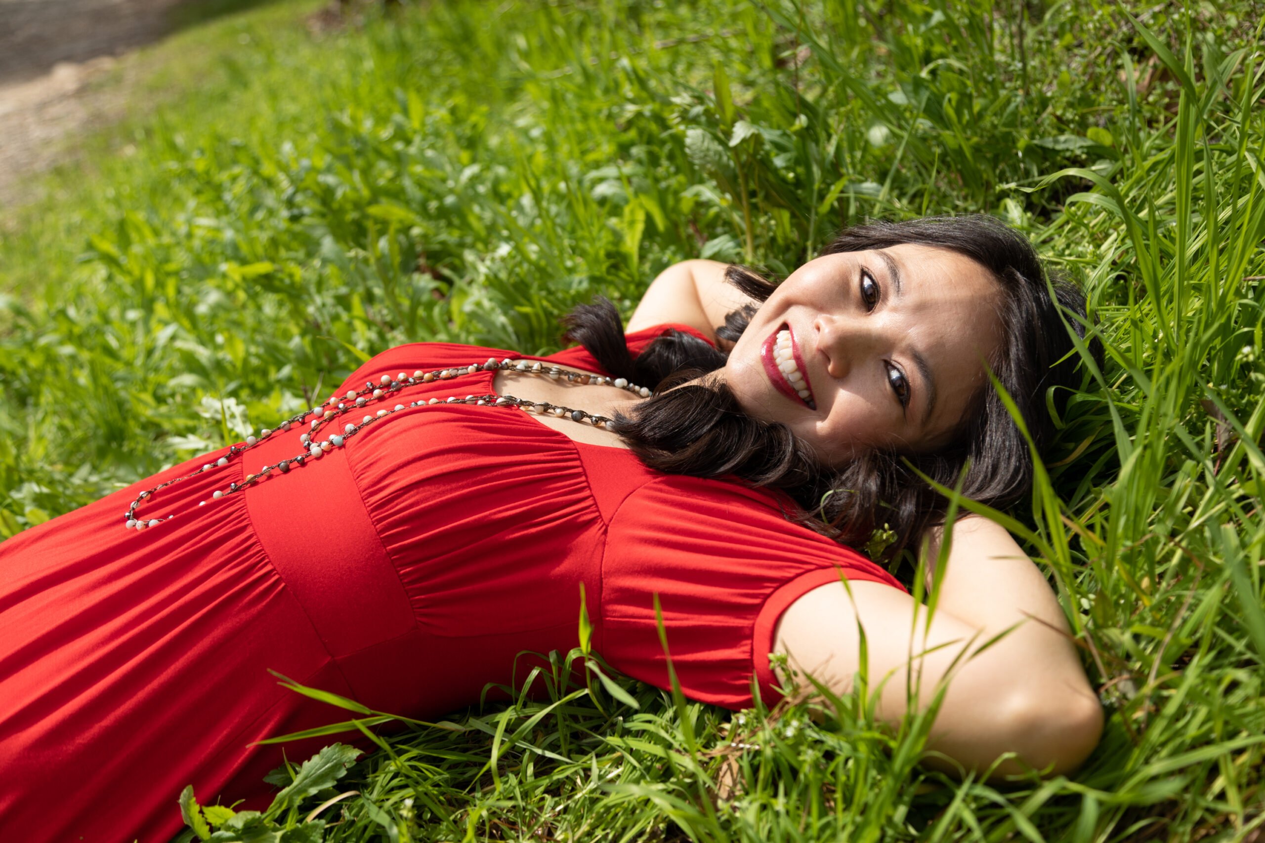 Patrick Heagney's portrait of Dr. Arlene Dijamco, laying on the grass in a red dress