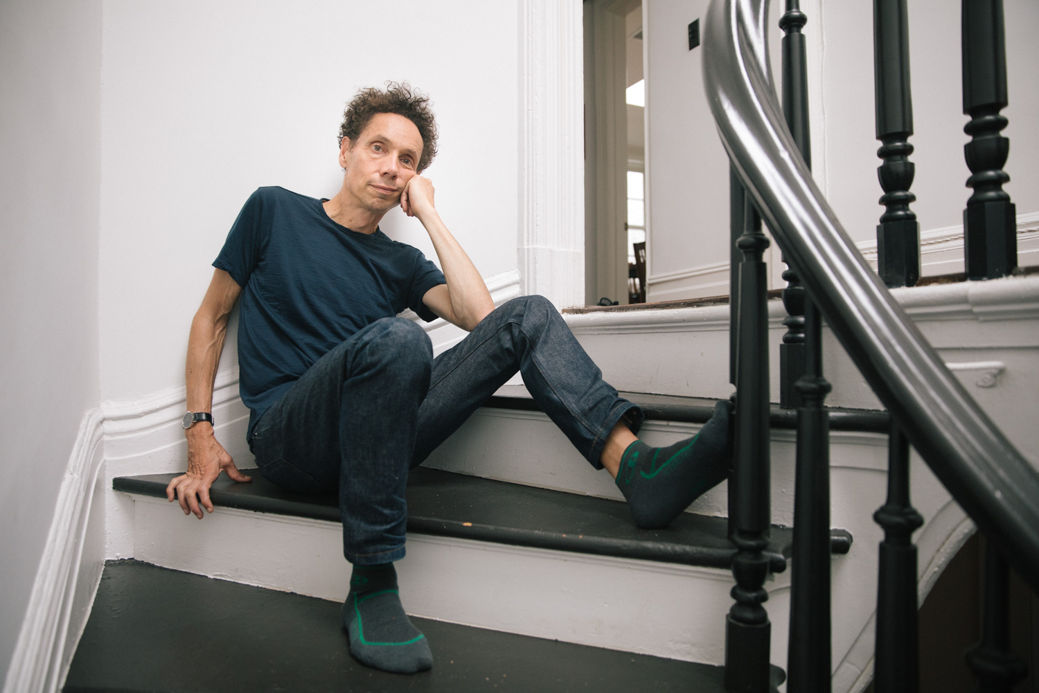 Photo of Malcolm Gladwell sitting on the stairs to his office.
