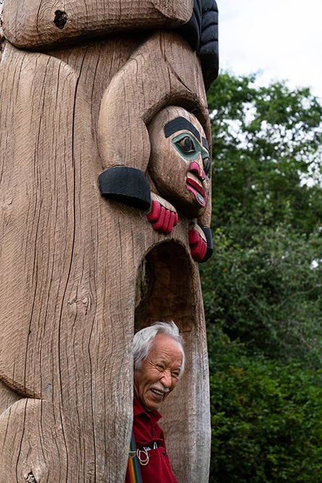 Artist at the bottom of a totem pole. Photography by Fernando Decillis for Smithsonian Magazine.