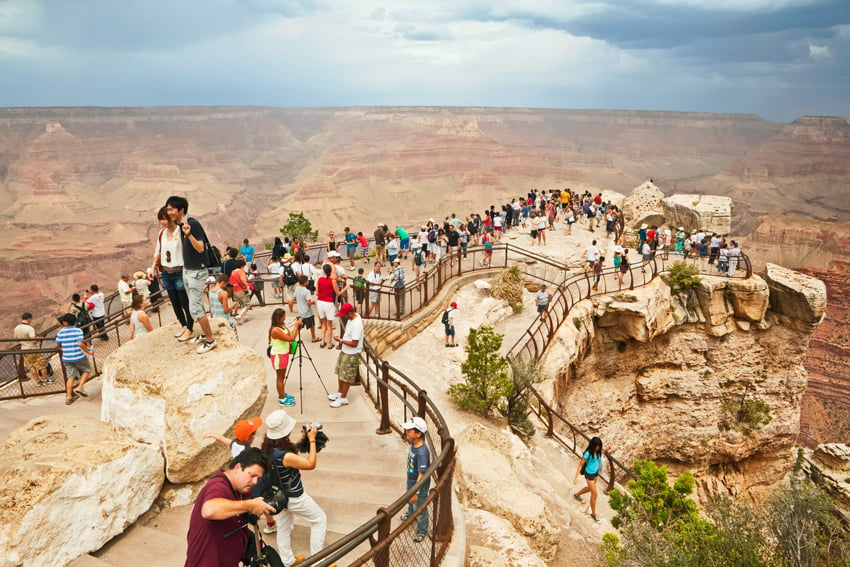 Dozens of tourists posing for pictures at the Grand Canyon by Giacomo Fortunato.
