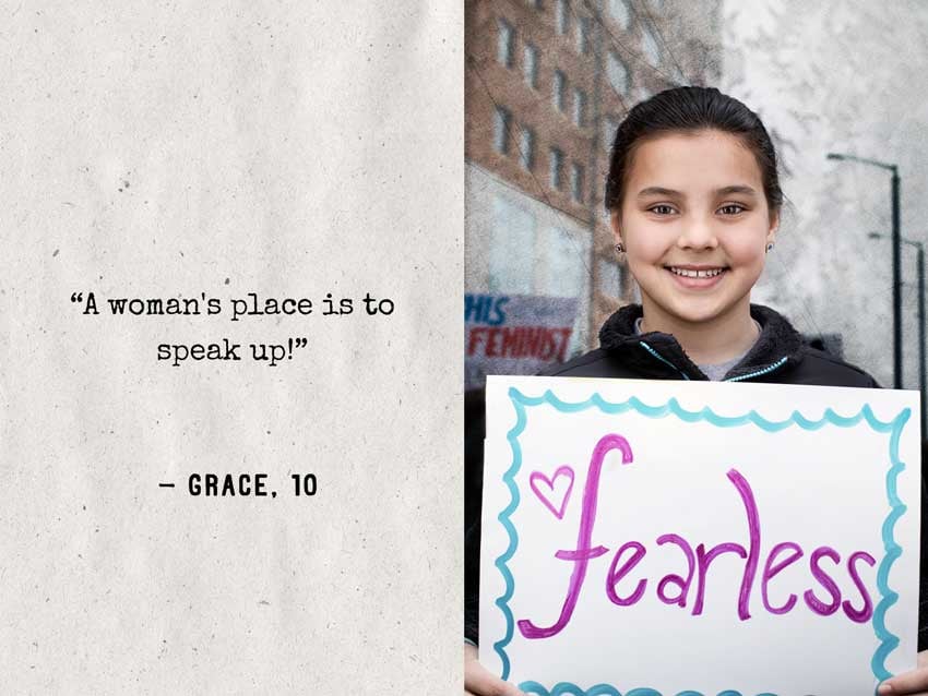 Natalia Weedy's portrait of a girl with dark hair pulled back and a sign that says "fearless."