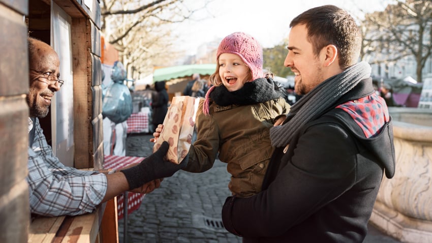 A father and his young daughter buying something at the Christmas market in Switzerland, photo by Guillaume Megévand.