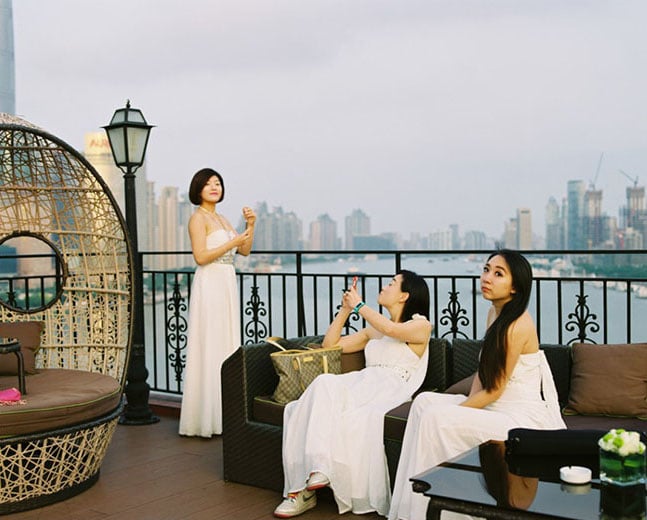 Three women dressed in bridal gowns lounge along the Huangpu river.