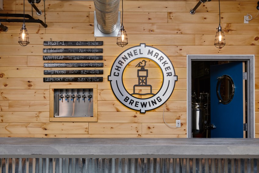 Interior shot of the brewery shows the list of available beers above the taps in the wall next to the logo