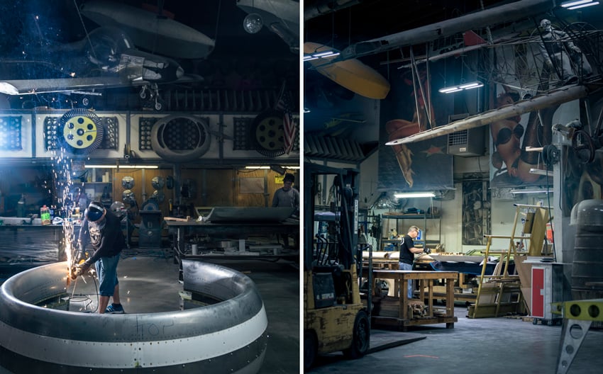 A diptych of Jeff Berting's photos of MotoArt craftsmen at work. On the left, a craftsman is soldering an airplane propeller. On the right is a photo of a craftsman working on something on a table on the left of the frame. The photo shows the quirkiness of the warehouse, with large pinup artwork on the walls and an airplane hanging from the high ceiling.