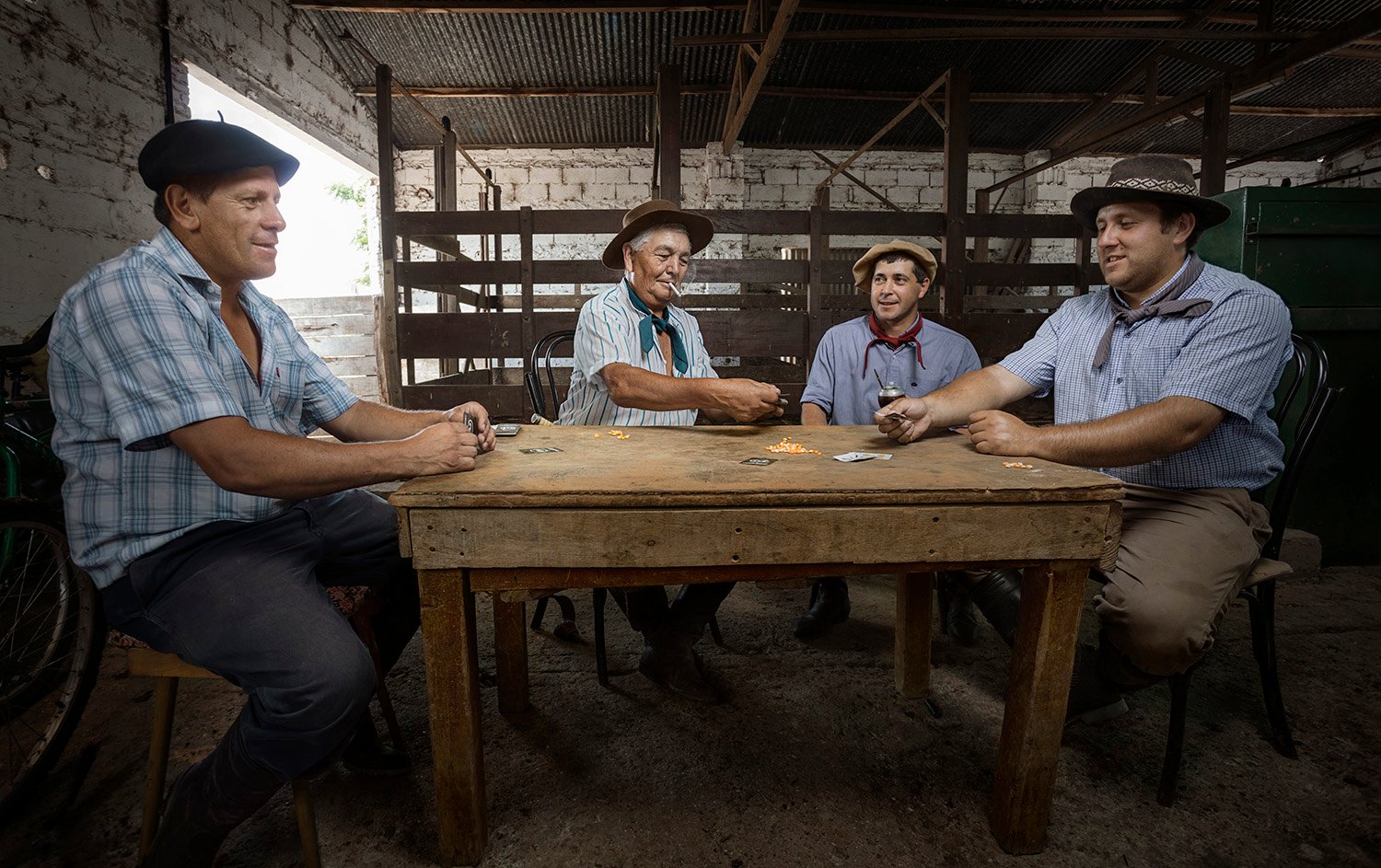 Jorge Oviedo's photo of four gauchos at a rustic wooden table in a stable playing cards.