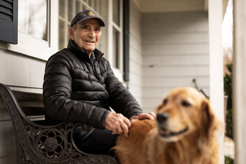 Josh Behan's COVID project Front Porchtrait captures an older man sitting on a bench with his golden retriever at his feet