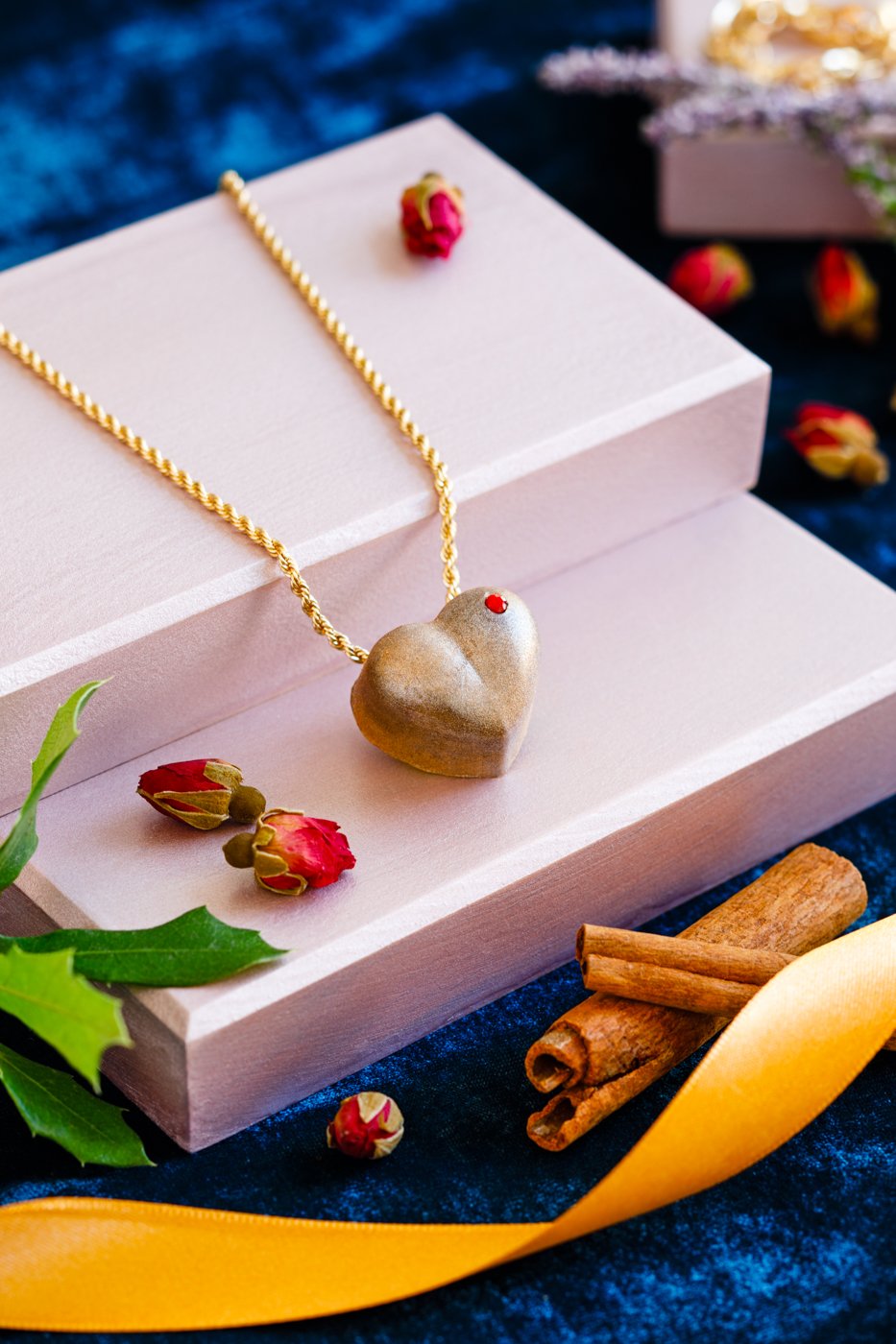 Gift boxes with a gold necklace and heart-shaped chocolate pendant laid across them.